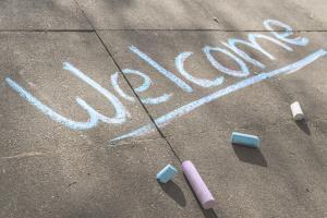 Das Wort "Welcome" mit Kreide auf den Boden geschrieben
